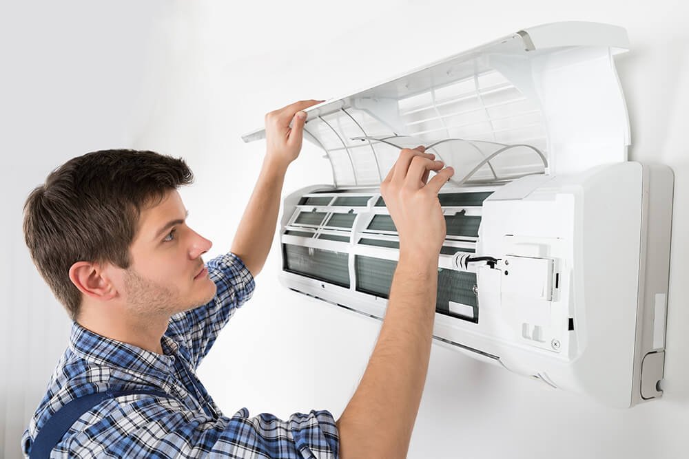 Technician inspecting and cleaning an open AC unit