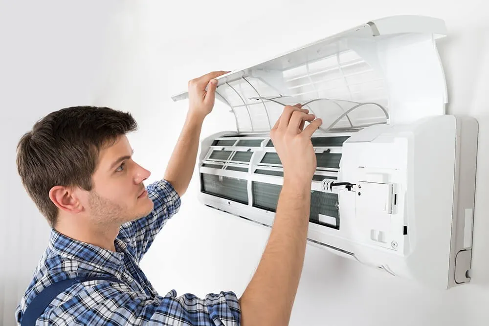 Technician inspecting and cleaning an open AC unit
